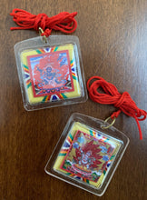 Load image into Gallery viewer, A clear square shaped amulet of the deity, Nam Jon. A red thread is attached to the amulet by a metal ringlet so it could be worn. The image of Nam Jon inside the amulet and decorated with thread details on the back. The amulet has smooth edges.