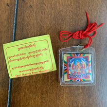 Load image into Gallery viewer, A clear square shaped amulet of the Loving Mother, Sherab Jamma. A red thread is attached to the amulet by a metal ringlet so it could be worn. The image of Sherab Jamma inside the amulet is colorful and decorated with thread details on the back. The amulet has smooth edges.